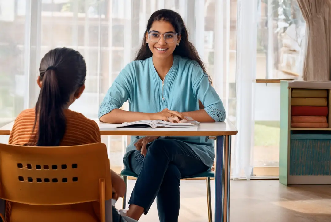 a tutoress who is the Best Home Tutor in Dwarka, sitting at a table with a book